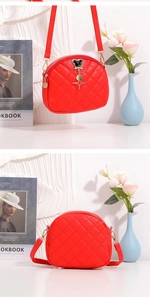 Détail du sac bandoulière demi-lune rouge matelassé avec pendentif étoile et breloque souris