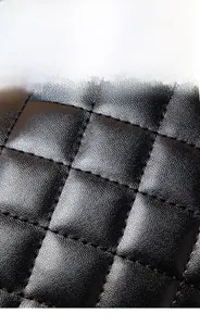 Close-up of black quilted PU leather texture with detailed lychee grain and stitching