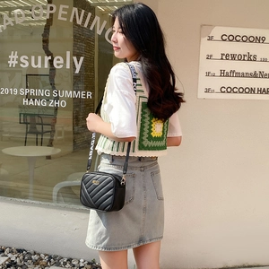 Black quilted leather camera bag with golden plaque and a wide BAG.19 fabric shoulder strap