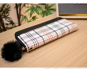 Detail of white checkered long wallet with black trim and fluffy pompom keychain