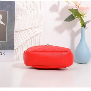 Détail du sac à bandoulière rond matelassé rouge avec fermetures éclair dorées élégantes
