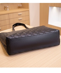 Detailed view of black quilted tote bag showing sturdy reinforced bottom and stitched seams
