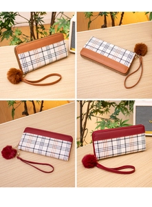Detailed view of plaid long wallets with fuzzy pom-poms and wristlets on a wooden table