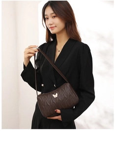 Close-up of quilted coffee shoulder bag featuring a golden butterfly metal clasp ornament