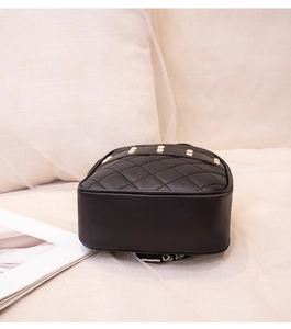 Detail of black quilted leather backpack base with gold studs and woven strap