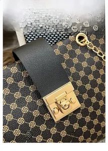 Detail of golden metal latch and clover pattern on vintage women's chain bucket bag