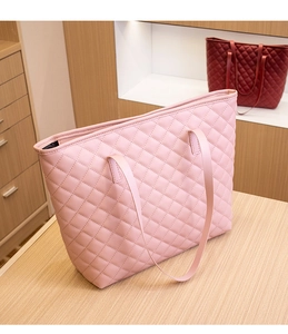 Detail shot of a pink quilted tote bag with diamond stitching on a wooden surface