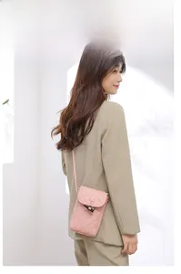 Detailed close-up of a pink quilted crossbody phone bag with an horn-style buckle closure