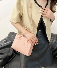 Detailed shot of pink faux leather handbag with V-quilted stitching and adjustable strap
