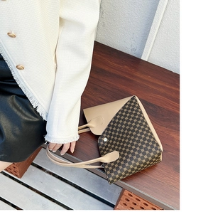 Dettaglio della borsa tote vintage in pelle beige con motivo geometrico marrone su panca