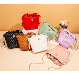 Détail de sacs seaux colorés avec matelassage en V et bandoulières en chaîne dorée