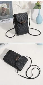Close-up of black quilted mini crossbody bag with amber-colored toggle buckle closure