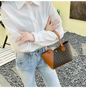 Dettaglio della borsa tote retrò con manici in pelle marrone portata da una modella