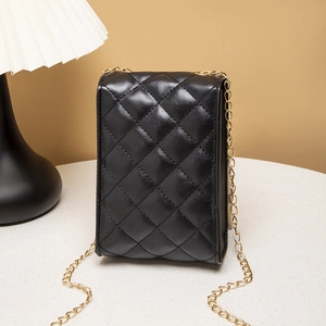 Quilted black chain crossbody bag with gold hardware on a stylish lifestyle background