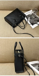 Detail of black V-quilted tote bag featuring gold hardware and detachable shoulder strap