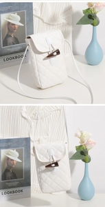 Close-up of white quilted crossbody phone bag featuring a vintage toggle buckle closure