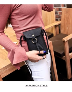 Close-up of black lychee grain mini crossbody bag with gold buckle and tassel on model
