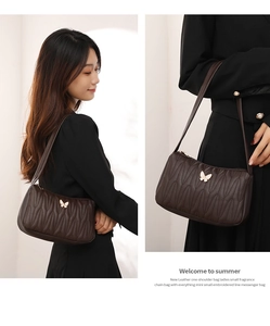 Close-up of brown embroidered crossbody bag with butterfly buckle and wavy stitching