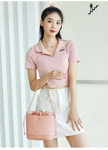 Détail du sac seau rose matelassé avec chaîne dorée et logo perlé porté par un mannequin
