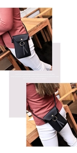 Detail of black pebbled leather crossbody phone bag with gold ring and tassel accents