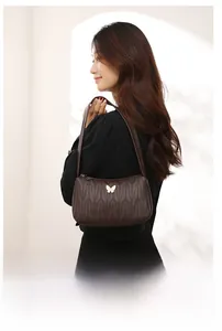 Detail of dark brown quilted shoulder bag featuring a gold butterfly metal emblem