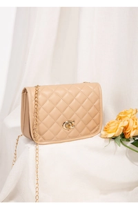 Detail of beige quilted flap bag with gold C-shaped metal lock and chain strap