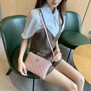 Pale pink quilted mini crossbody bag with gold hardware shown on a model in a modern setting