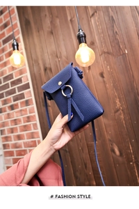 Detail of navy blue pebble leather mini bag with decorative gold metal ring closure