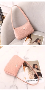 Detail of pink quilted PU leather shoulder bag with wave stitching and butterfly clasp
