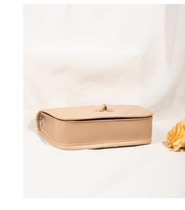 Detail view showing bottom and side structure of beige quilted crossbody bag with gold lock