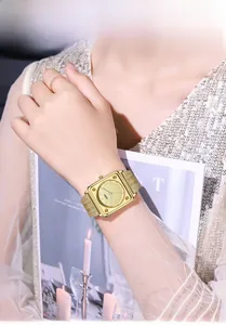 Close-up of elegant gold square watch with Milanese band on wrist with lifestyle props