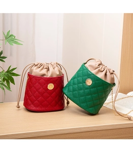 Detailed view of red and green bucket bags with drawstring closure and metal chain strap