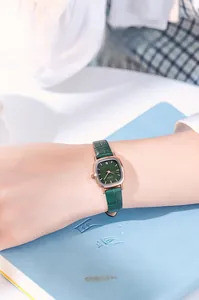 Close-up of elegant green square dial ladies watch with gold case and leather strap