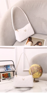 Detail of white quilted underarm bag with gold butterfly hardware on diverse surfaces