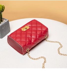 Detail of red quilted crossbody bag with gold chain strap and metal turn-lock closure