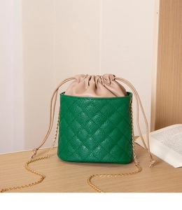 Detailed view of green quilted bucket bag with beige drawstring and gold chain strap