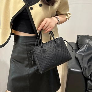 Elegant black leather handbag with V-shaped stitching and versatile shoulder strap