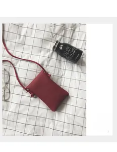 Detail of minimalist dark red pebble grain leather phone crossbody bag with knotted strap