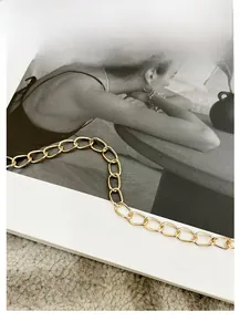 Detailed macro shot of the polished gold metal chain strap on a quilted bucket bag