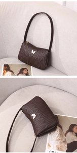 Detailed view of dark brown PU leather bag with golden butterfly buckle and quilting