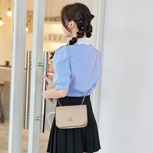 Women's chic beige quilted chain crossbody bag paired with blue plaid puff sleeve shirt