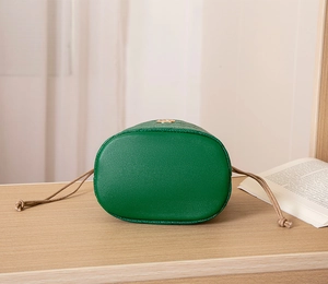 Detailed base view of emerald green litchi grain leather bucket bag with braided drawstring