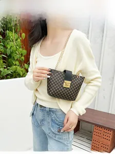 Detail of elegant chain strap and gold square buckle on a textured crossbody bucket bag