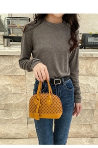 Detail of yellow shell handbag with retro floral print and leather decorative tag