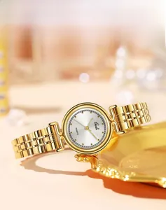 Elegant gold metal women watch with sunray dial displayed on a decorative golden tray