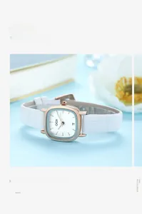 Detail of a rose gold square watch with a white leather strap and a date window display
