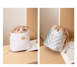 Detail of quilted bucket bags in white and silver featuring gold chain straps and drawstrings