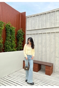 Chic brown checkered chain bucket bag styled with a yellow cardigan and denim jeans