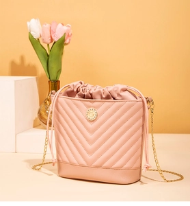 Détail du sac seau rose brodé avec simili cuir surpiqué en V et bandoulière chaîne dorée