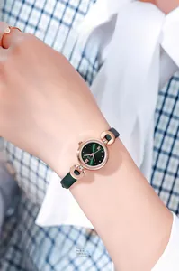 Gros plan d'une élégante montre femme en or rose avec cadran vert et bracelet en cuir